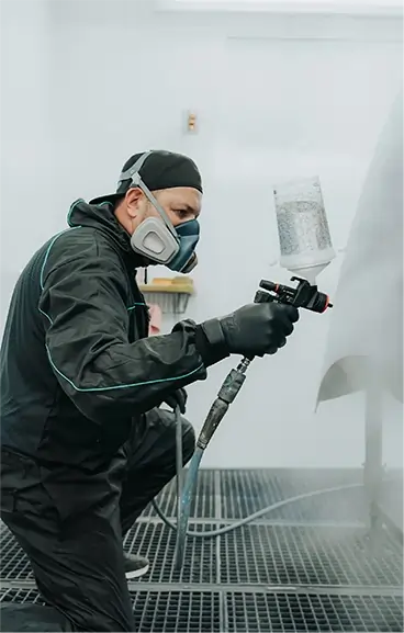 Mitarbeiter lackiert ein Karosserieteil